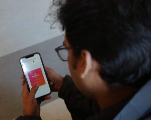 En man tittar på sin mobiltelefon som visar en röd ruta med text på en vit bakgrund.
