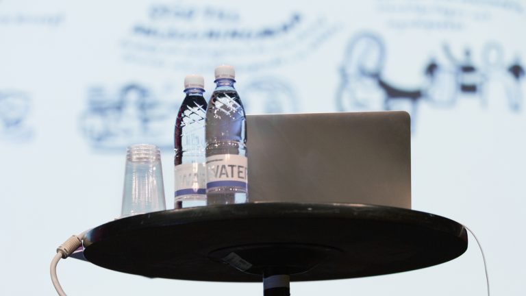Ett talarbord med dator och två vattenflaskor.