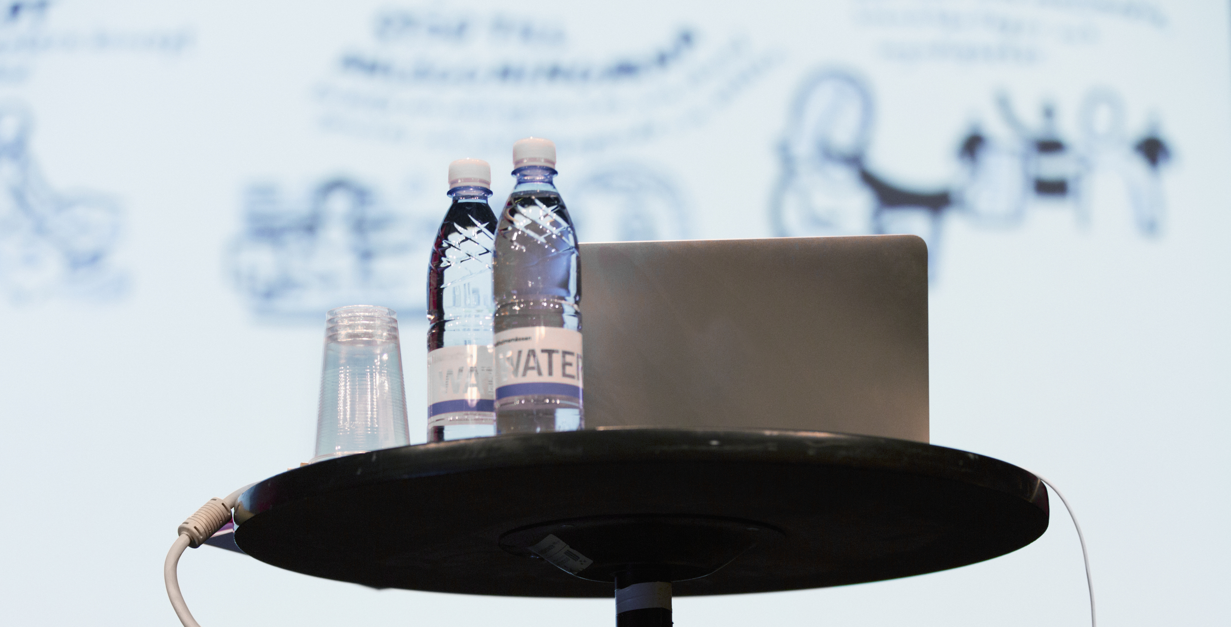 Ett talarbord med dator och två vattenflaskor.