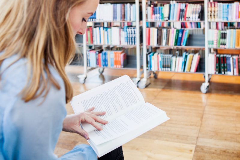 En kvinna läser en bok i ett bibliotek